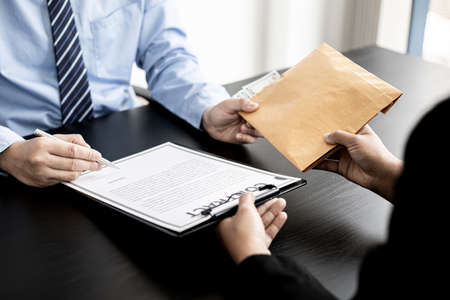 Business men are signing agreements for conspiracy to corrupt and receiving money for bribery in an upcoming big project, corruption is illegal and immoral. The concept of corruption.の写真素材