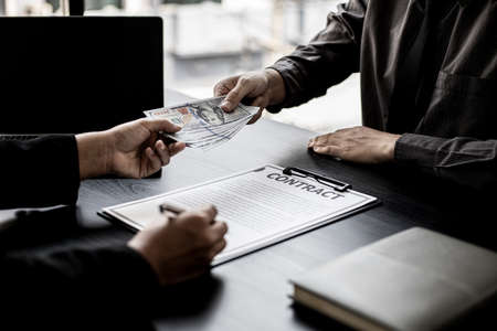 The company's procurement manager is contracting a partner company, accepting large amounts of bribes in dollar bills to cooperate in defrauding the company, fraud is illegal and immoral.の写真素材