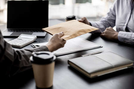 Two businessmen are handing out envelopes, two businessmen are working together to corrupt the company, corruption is illegal and immoral. The concept of corruption.の写真素材