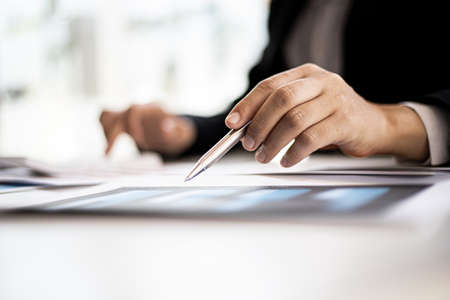 Businessmen are examining company financial information from documents prepared by the finance department, financial documents placed on their desks displayed in bar charts. Financial concept.の写真素材