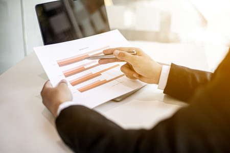 Businessmen are examining company financial information from documents prepared by the finance department, financial documents placed on their desks displayed in bar charts. Financial concept.の写真素材