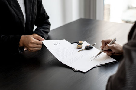 An employee of the rental car company submits a car rental agreement for the renter to sign the...