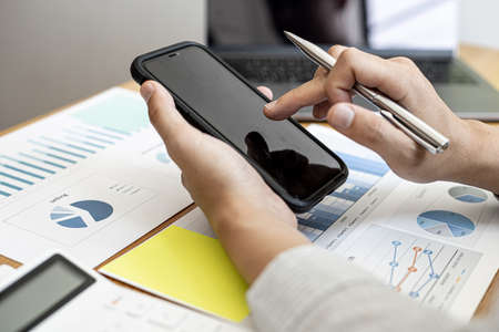 A businessman is using a smartphone to type text messages to his partners in a messaging app. Online messaging is very popular and convenient nowadays. Concept of using technology in communication.の写真素材