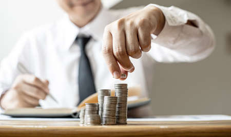 Businessmen are stacking coins on top of the highest row, saving money for growth by taking their monthly savings to fund or invest. Concept of saving money for investment.の写真素材