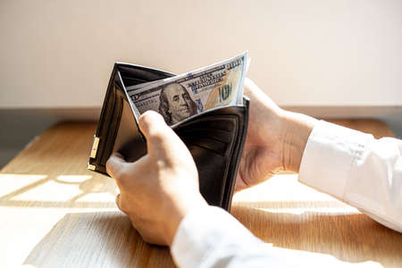A man is opening a wallet with a dollar bill inside, he is about to take the money out of the wallet to pay for the food. Personal finance concept.の写真素材