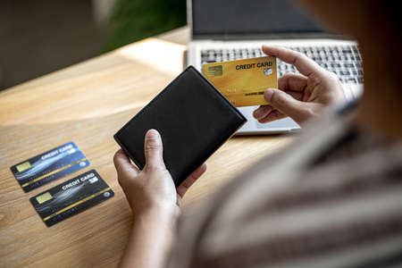Women are taking their credit cards out of their wallets to pay for the goods they ordered through the website. Credit cards can pay for products online. Online shopping ideas.の写真素材