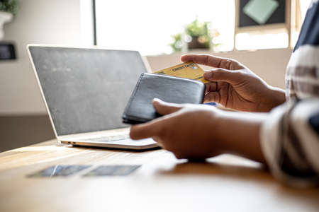 Women are taking their credit cards out of their wallets to pay for the goods they ordered through the website. Credit cards can pay for products online. Online shopping ideas.の写真素材