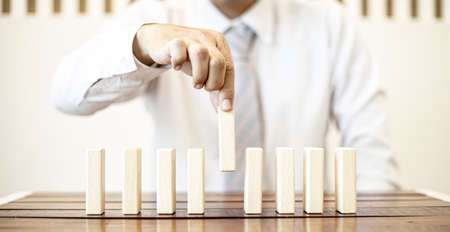 A close-up shot of a businessman holding the wooden blocks in a row, the wood blocks compare to the business risk management. The concept of risk management. copy space.の写真素材