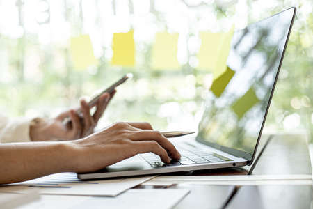 A businesswoman is using a laptop to check company financial information, she is checking company financial information from the documents provided by the finance department. Financial concept.の写真素材