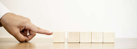 A businessman pushes the wooden blocks with their fingers to form a neat row, copy space.の写真素材