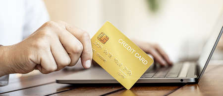 Man is holding a credit card to fill out the information on laptop. They are filling out credit card information for online shopping, credit cards are used to pay for products through online stores.の写真素材
