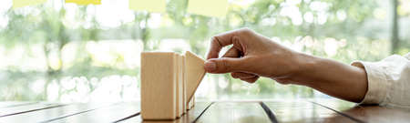 A close-up shot of a businessman holding the wooden blocks in a row, the wood blocks compare to the business risk management. The concept of risk management. copy space.の写真素材