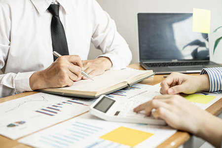 Two businessmen are working together to brainstorm how to grow the company and make plans to control the company's finances in accordance with the plan. Financial concept.の写真素材
