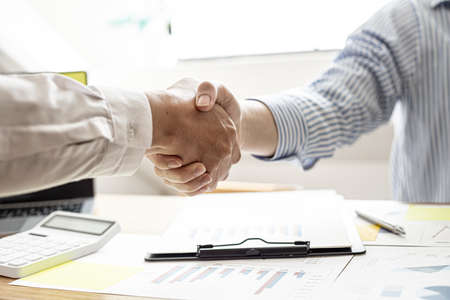 Business partners are holding hands after discussing the company's finances, together they...