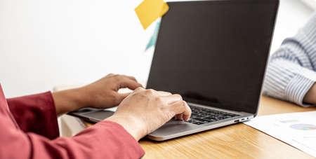 A business woman is typing on a laptop keyboard, documenting monthly sales, before meeting with the manager to summarize the performance. Sales management concept.の写真素材