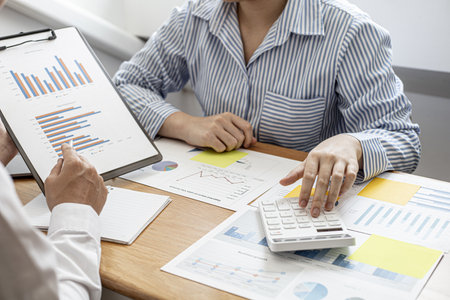 Business women are pressing a to check together with male business partners, they are documenting company finances and verifying the accuracy of the information. Financial concept.の写真素材