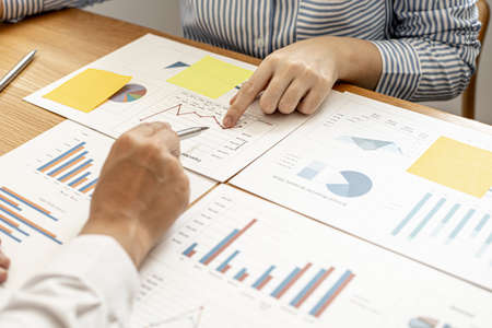 Two businessmen are examining the information in the company's financial documents provided by the finance department, they brainstorm to develop the company to further growth. Financial concept.の写真素材