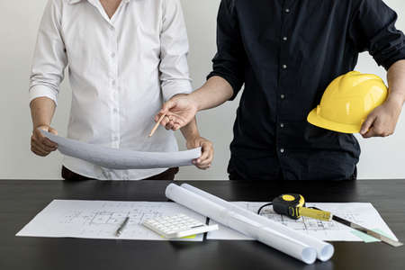 Architects and engineers are discussing house plans designed to verify accuracy and to meet design and construction standards. Interior design and decoration ideas.の写真素材