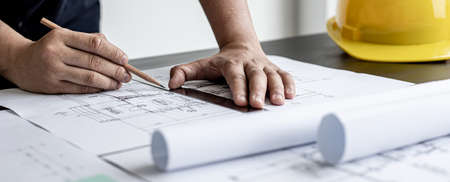 An architect, a home design engineer, is drafting a house plan for a client in his office. He is writing a house plan based on the needs of his clients. House building and interior ideas.の写真素材