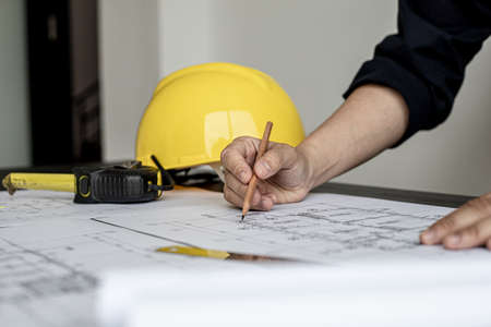 The architect and engineer are drawing up the drawings of the house according to the project received. He works in his office, he does the design according to the needs of the clients.の写真素材