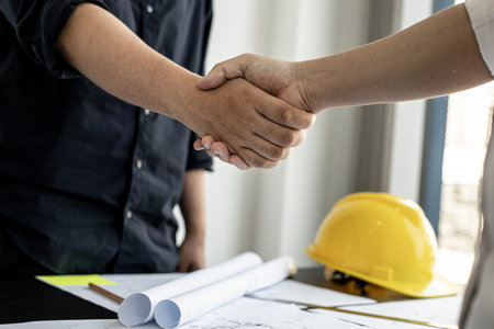 A team of architects and engineers in a big project went hand in hand after meeting on building plans. Construction and interior ideas.の写真素材