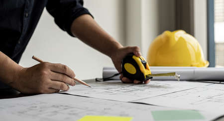 The architect and engineer are drawing up the drawings of the house according to the project received. He works in his office, he does the design according to the needs of the clients.の写真素材