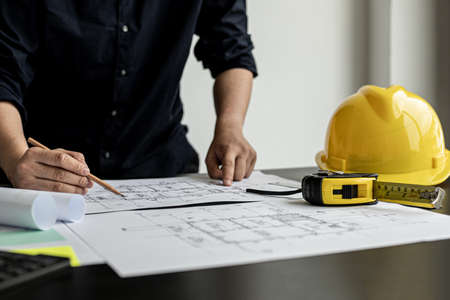 The architect and engineer are drawing up the drawings of the house according to the project received. He works in his office, he does the design according to the needs of the clients.の写真素材