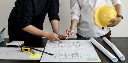 Two architects and engineers are in a meeting to discuss house designs according to building and...