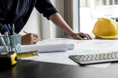 The architect and engineer are drawing up the drawings of the house according to the project received. He works in his office, he does the design according to the needs of the clients.の写真素材