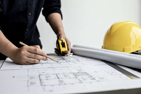The architect and engineer are drawing up the drawings of the house according to the project received. He works in his office, he does the design according to the needs of the clients.の写真素材