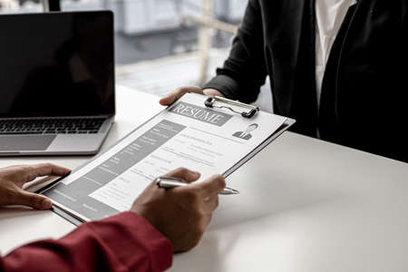 The job applicant is submitting a resume to the manager for a job interview. The concept of a job interview in a position that matches the candidate's qualifications and abilities.の写真素材