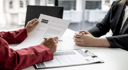 The manager is interviewing job applicants and reading the candidate's personal information on the resume. The idea of recruiting to recruit people to work in the missing position.の写真素材
