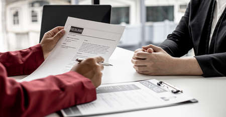 The manager is interviewing job applicants and reading the candidate's personal information on the resume. The idea of recruiting to recruit people to work in the missing position.の写真素材