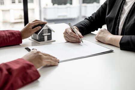 The tenant is signing a lease agreement with the landlord after viewing the home and discussing the rental agreement details. Real estate rental ideas.の写真素材