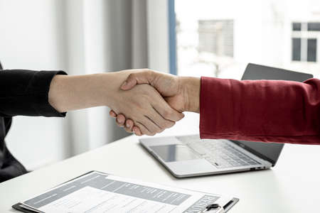 The job interviewer and the job applicant are holding hands after the job interview is finished. The concept of recruiting employees to work in the company, vacant positions.の写真素材