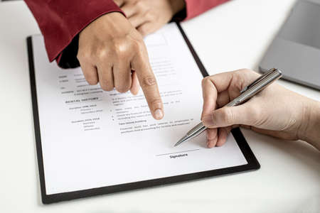 The HR department is pointing to the documents for the job applicant to sign on the contract after attending a job interview with the department manager and being selected for the job.の写真素材