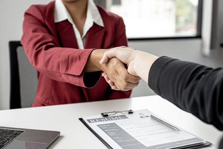 The job interviewer and the job applicant are holding hands after the job interview is finished. The concept of recruiting employees to work in the company, vacant positions.の写真素材