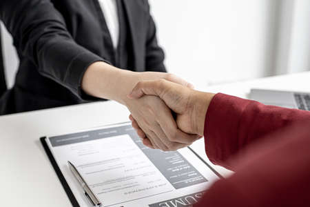 The job interviewer and the job applicant are holding hands after the job interview is finished. The concept of recruiting employees to work in the company, vacant positions.の写真素材