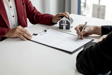 The tenant is signing a lease agreement with the landlord after viewing the home and discussing the rental agreement details. Real estate rental ideas.の写真素材