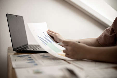 Businesswoman examining company financial documents during a meeting with shareholders, corporate finance documents showing a bar graph format prepared by the company's finance department.の写真素材