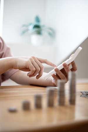 A woman is using a calculator to calculate money, she is doing an income and expenditure account to...