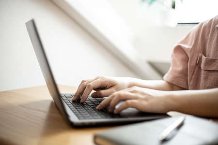 Close-up of a business woman typing on a laptop keyboard, a business woman using a laptop to chat with a partner via a messaging application. Concept of using technology in communication.の写真素材