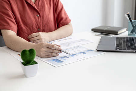 A corporate finance employee is pointing at the document with a pen to verify the accuracy of the financial documents that have been prepared for the meeting with management. Financial concept.の写真素材