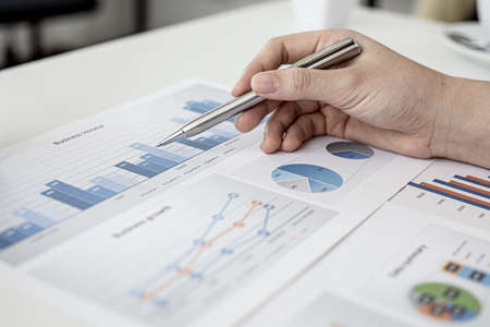 A corporate finance employee is pointing at the document with a pen to verify the accuracy of the financial documents that have been prepared for the meeting with management. Financial concept.の写真素材