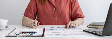 A business finance woman is reviewing a company's financial documents prepared by the Finance Department for a meeting with business partners. Concept of validating the accuracy of financial numbers.の写真素材