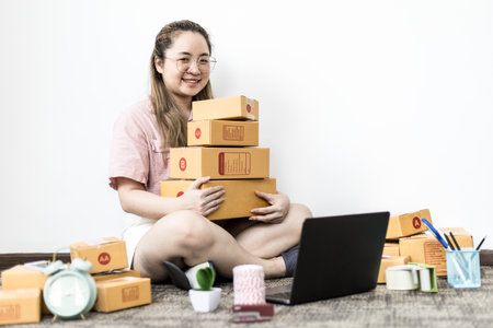 The online merchant is picking up many packages after packing orders and is about to deliver them to customers through a private shipping company. Concept of online selling and shipping.の写真素材