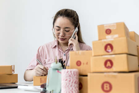 Employees are writing customer shipments to order products through online websites and deliver products through private transportation services. Product sales concepts online.の写真素材