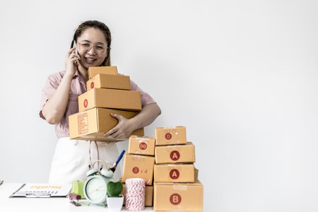 Online trading women stand holding a large number of parcel box and talk on the phone, she is...