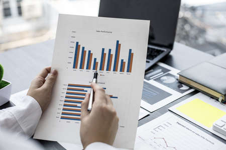 The sales manager pointing at the sales document, she is reviewing the monthly sales report of the...
