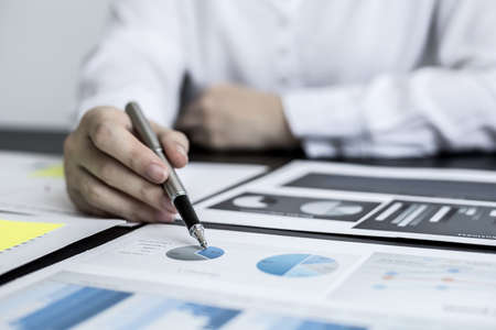 A close-up businesswoman holding a pen and pointing at a company financial statement, she is checking monthly financial documents from the finance department. The financial concept of the company.の写真素材